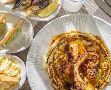 Delicious fine dining seafood platter featuring grilled octopus and fresh sides served on elegant tableware.